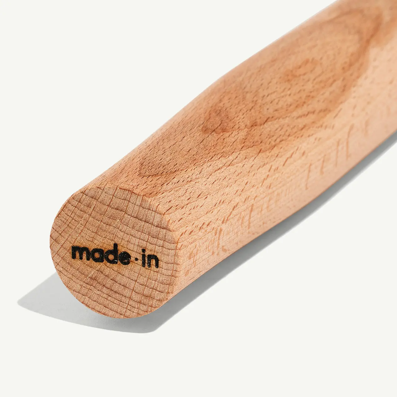 A close-up view of a wooden object with the words "made in" stamped on its end.