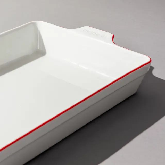 Red rimmed rectangle bakeware on grey background
