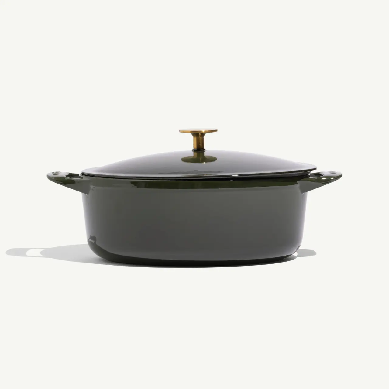 A dark green enameled cast iron pot with a gold-colored knob on the lid.