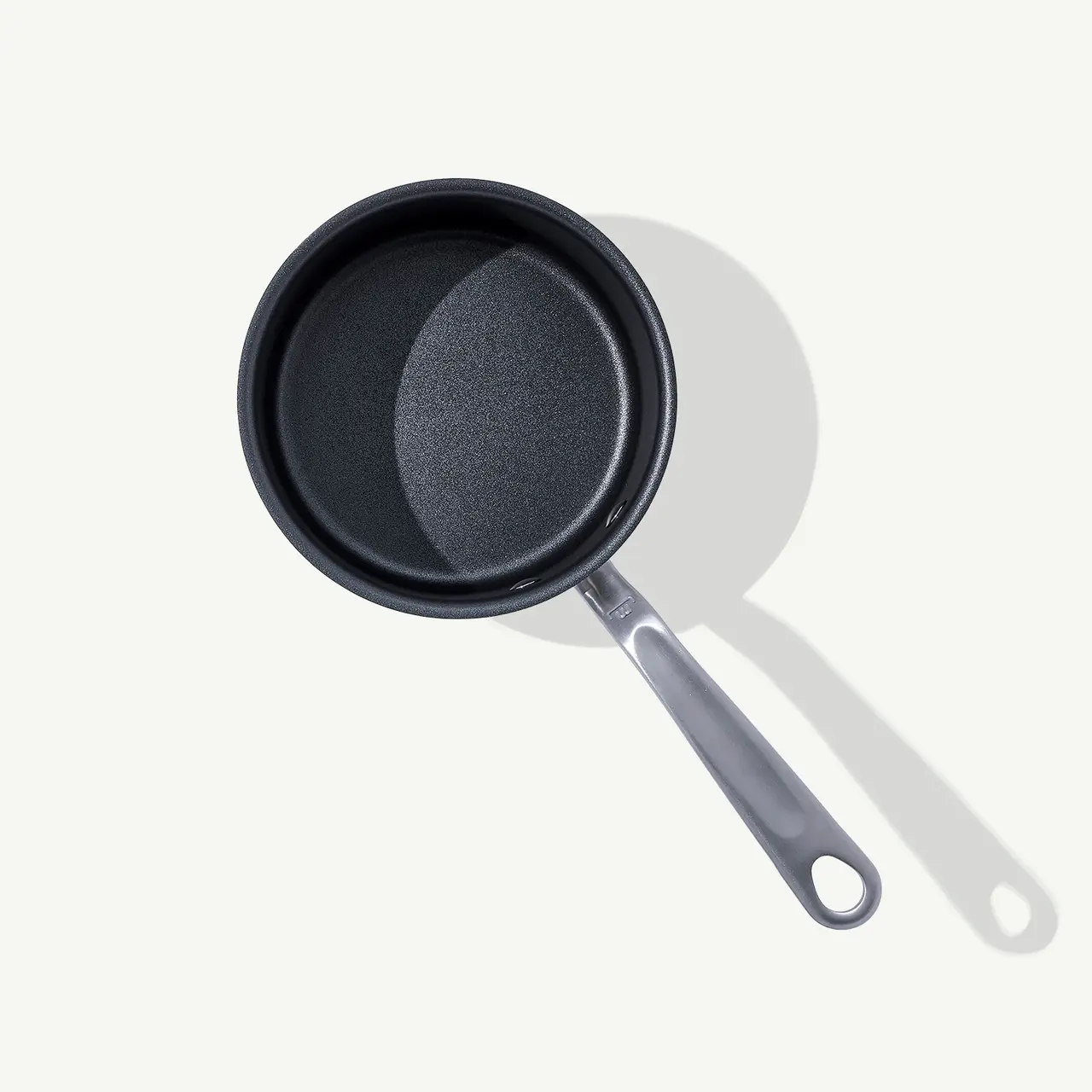 A non-stick frying pan is centered on a light background, casting a soft shadow.