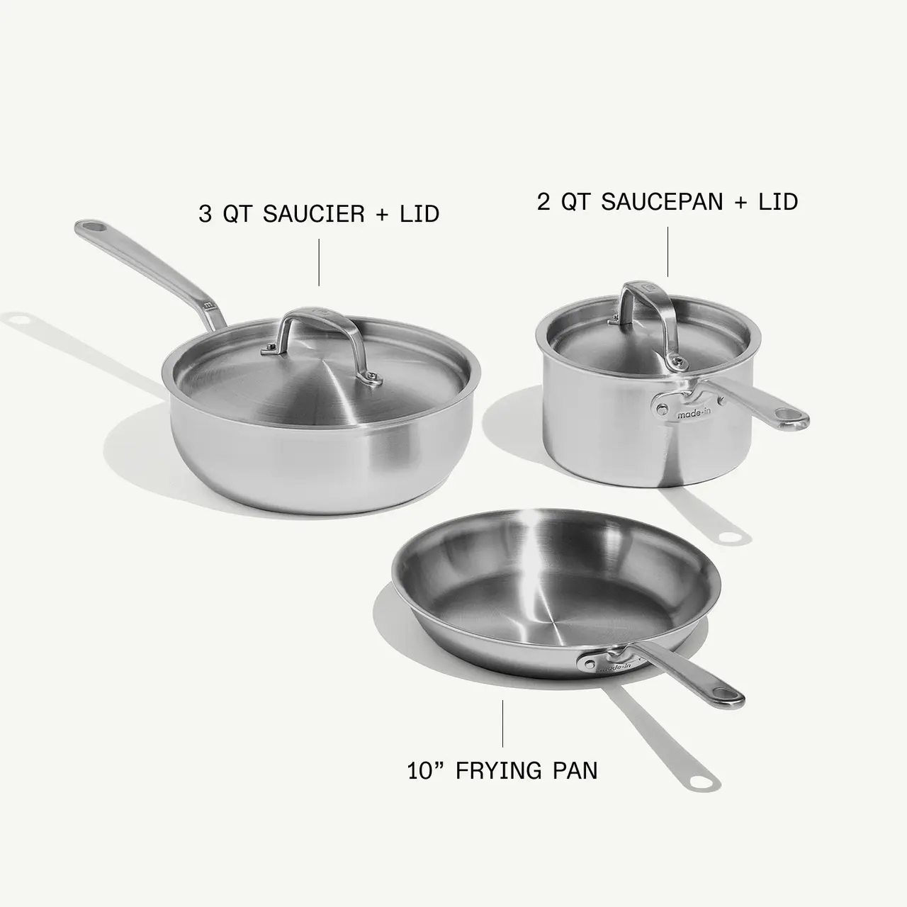 A stainless steel cookware set features a 3-quart saucier with a lid, a 2-quart saucepan with a lid, and a 10-inch frying pan.