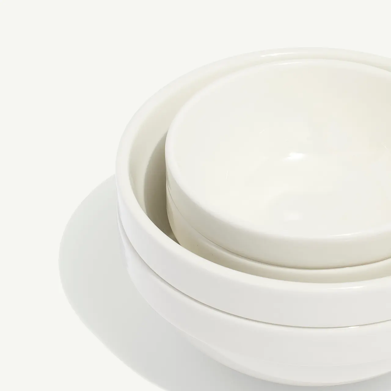 Stacked white ceramic dishes on a plain background display a simple and clean design.