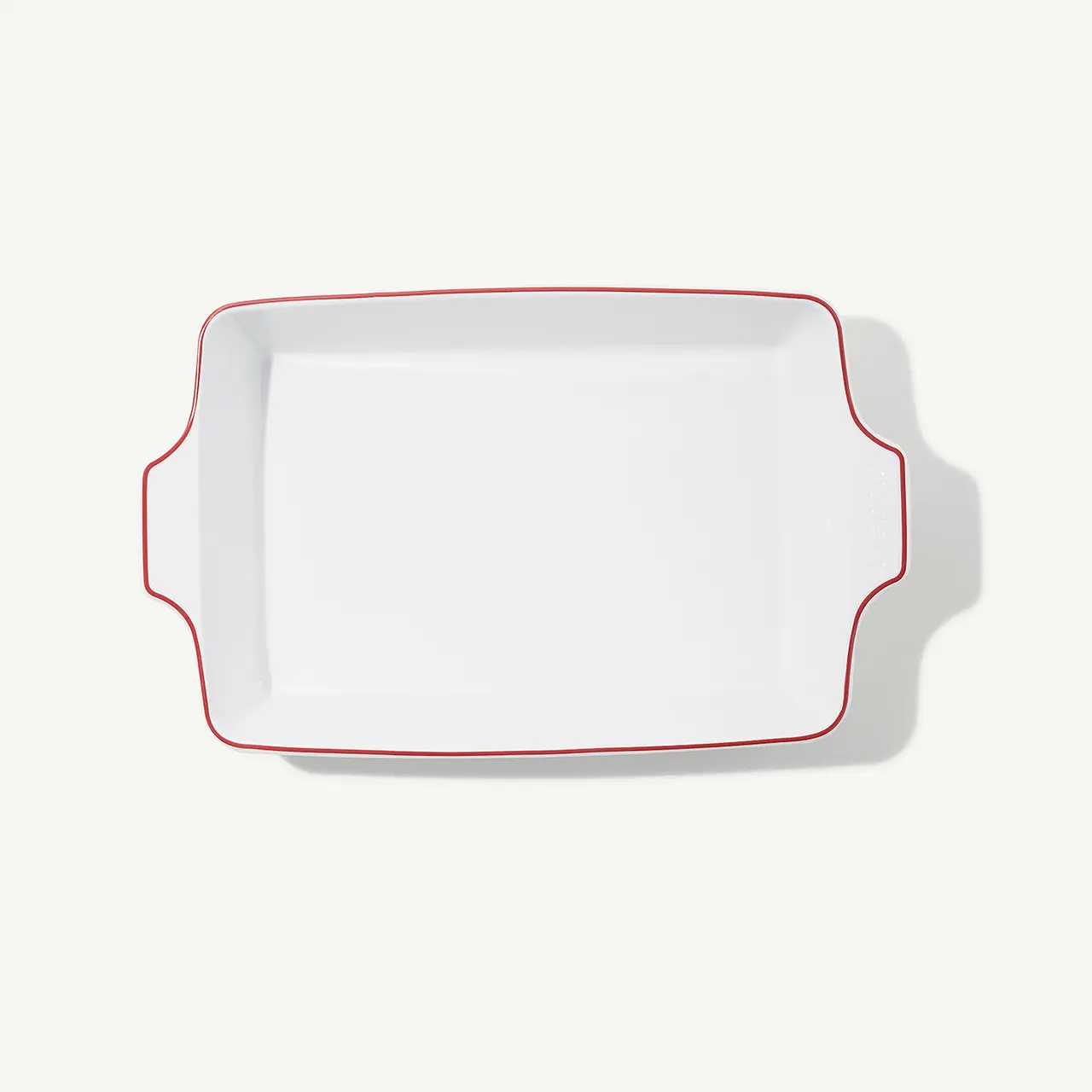 A white rectangular serving platter with scalloped edges and a red outline sits against a solid background.