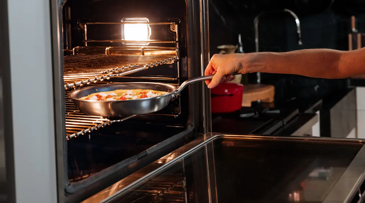A person is placing a pan with food into an oven.