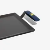 A rectangular cast iron griddle with a blue handle featuring a gold "M" logo.