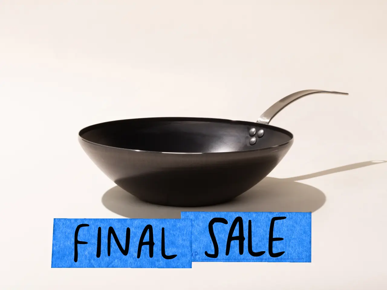 A black frying pan is featured against a neutral background with a blue "FINAL SALE" sign placed in front of it.