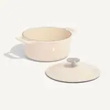 A cream-colored cooking pot with its lid placed to the side on a light background.