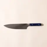 A chef's knife with a dark blade and a blue handle lies against a light background.