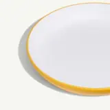 A round, white plate with a bright yellow rim sits against a light background.