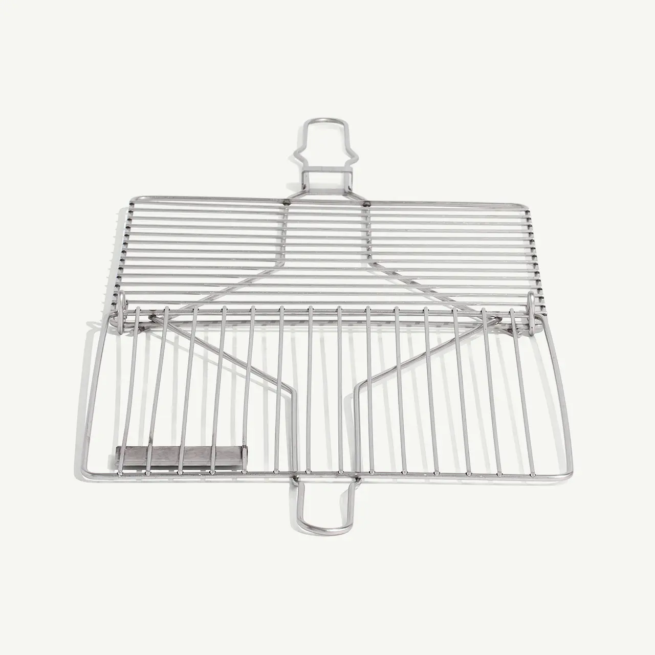 A stainless steel fish grilling basket lies against a white background.
