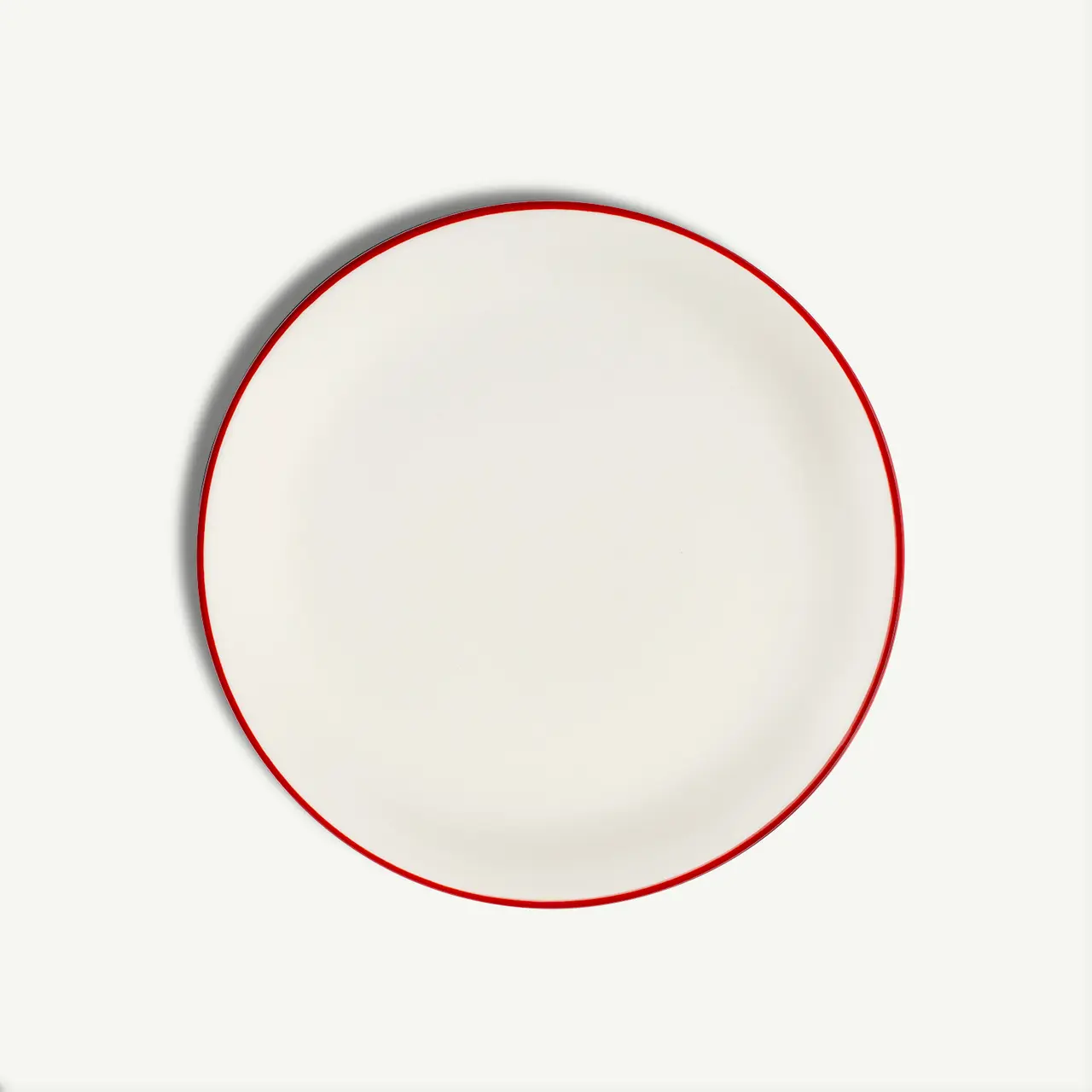 A plain white round plate with a simple red rim on a white background.