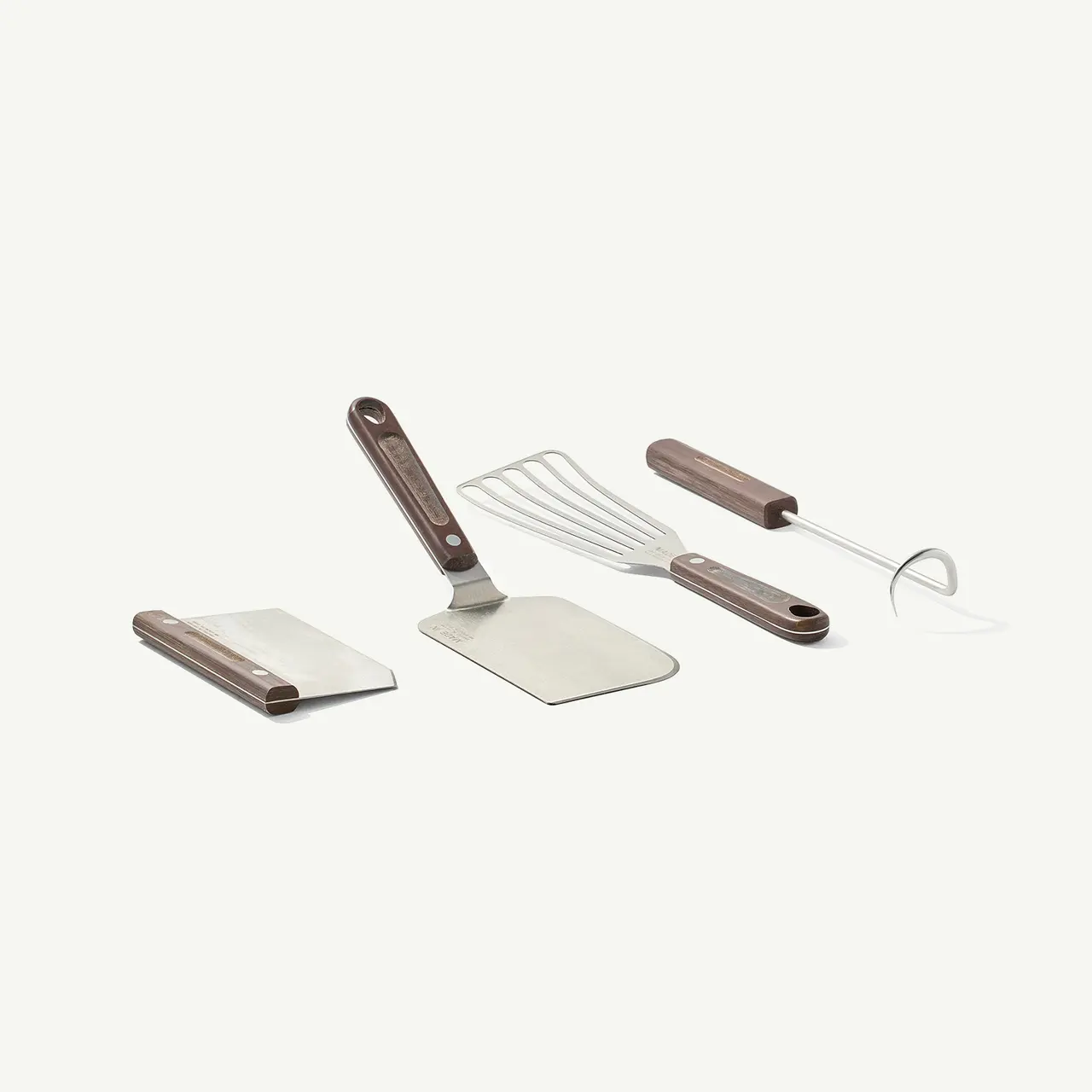 A set of cheese knives and slicers with wooden handles are arranged on a light background.