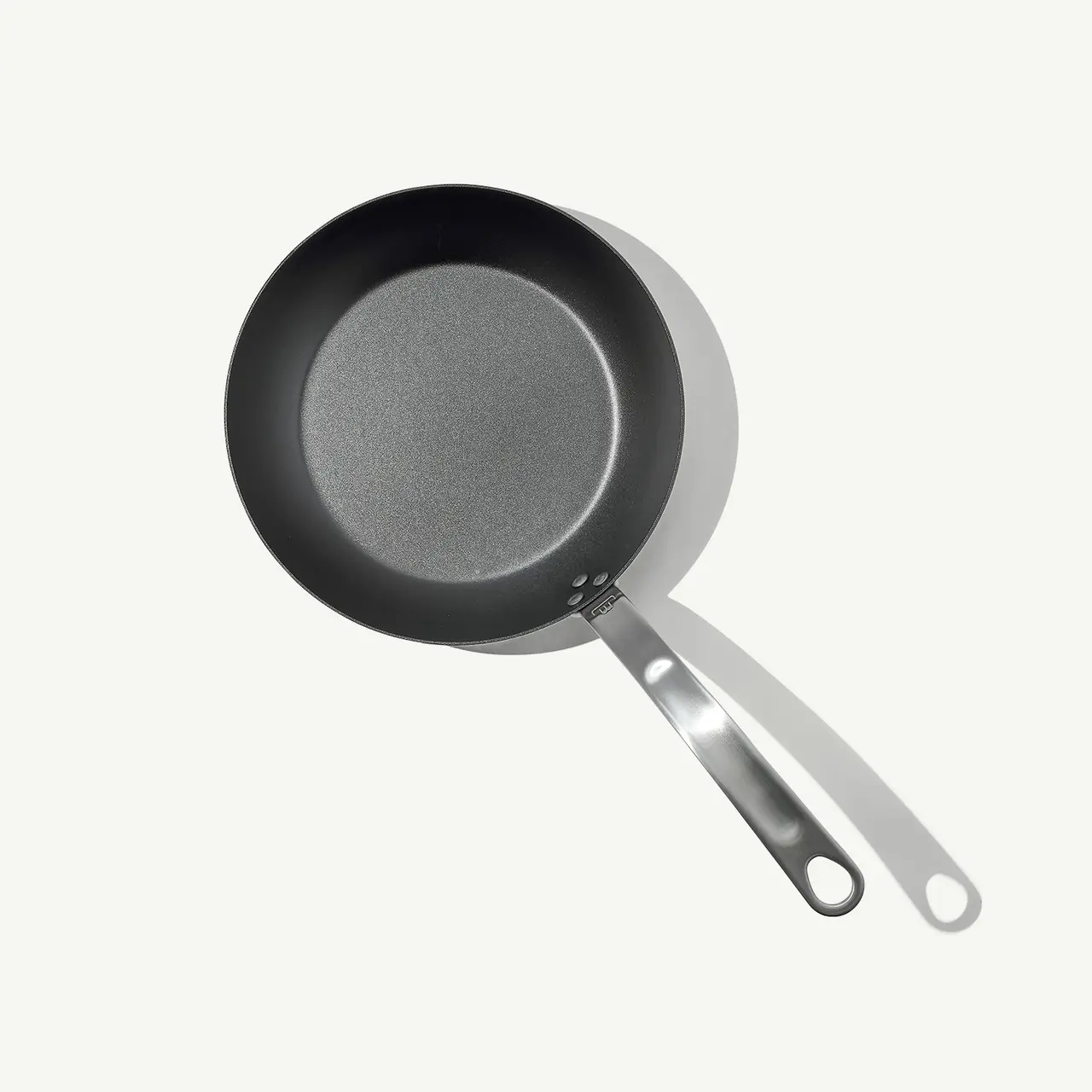 A non-stick frying pan with a silver handle lies against a light gray background.