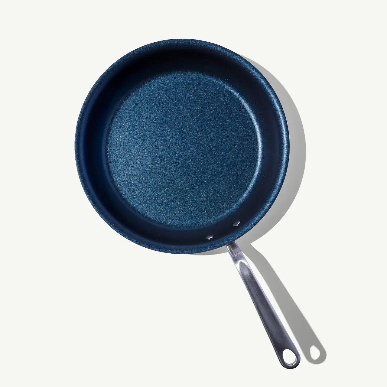 A non-stick frying pan with a silver handle is seen from above on a light background.