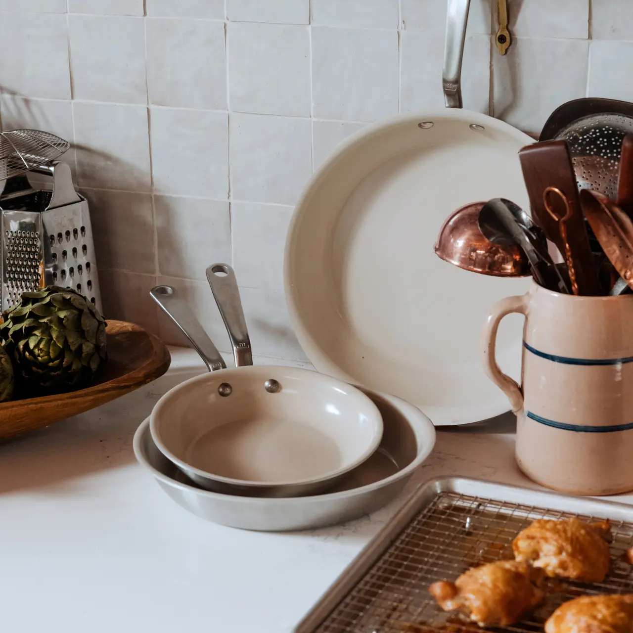 A variety of cooking utensils and dishes are arranged on a kitchen counter, suggesting food preparation or the aftermath of cooking.