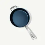 Two frying pans with white handles are overlaid on each other against a light background.