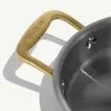 A stainless steel pot with a brushed finish and a gold-colored handle.