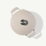 A beige-colored pan is viewed from above, displaying its handle and a silver circular detail at the center.