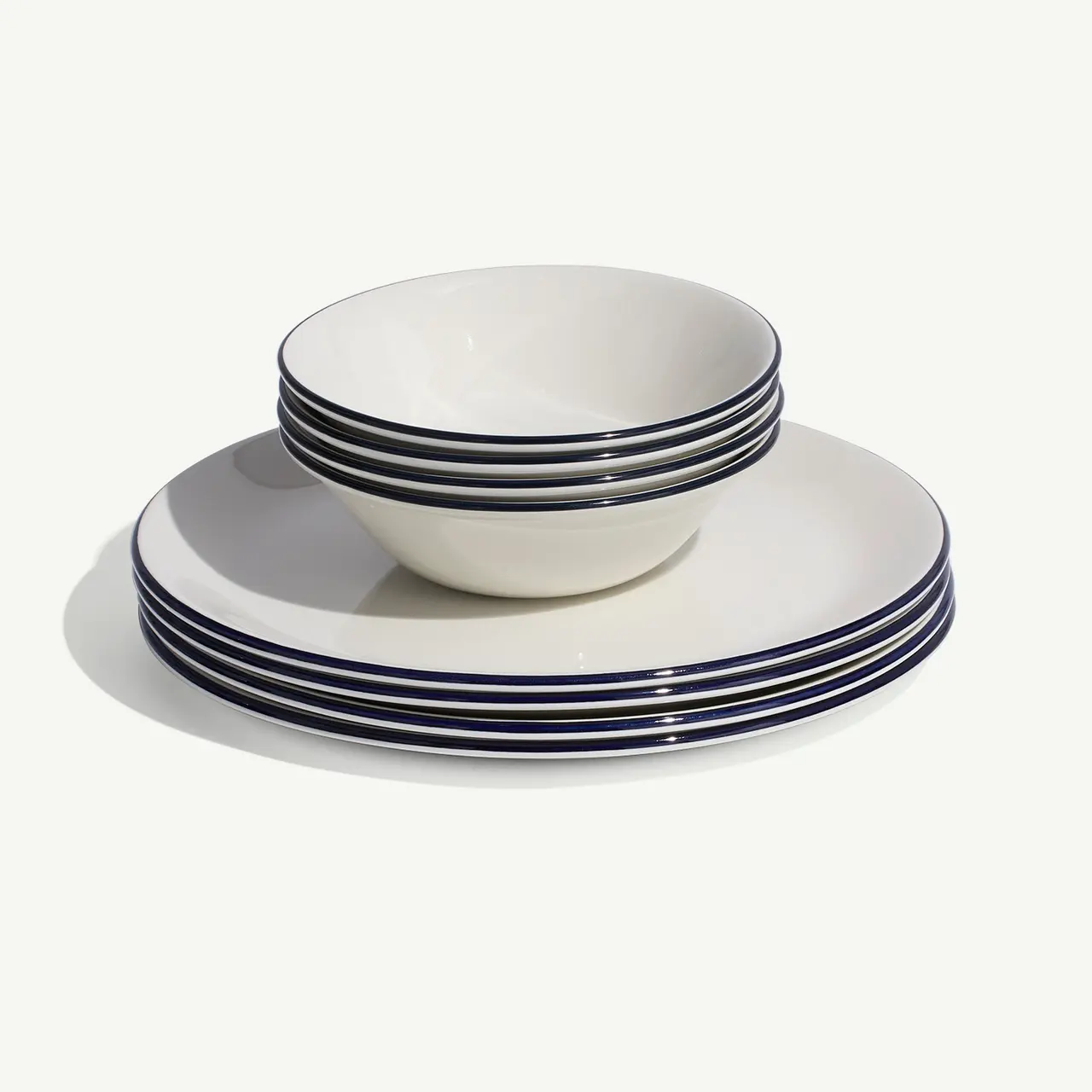 A stack of white plates and bowls with blue stripes on a plain background.