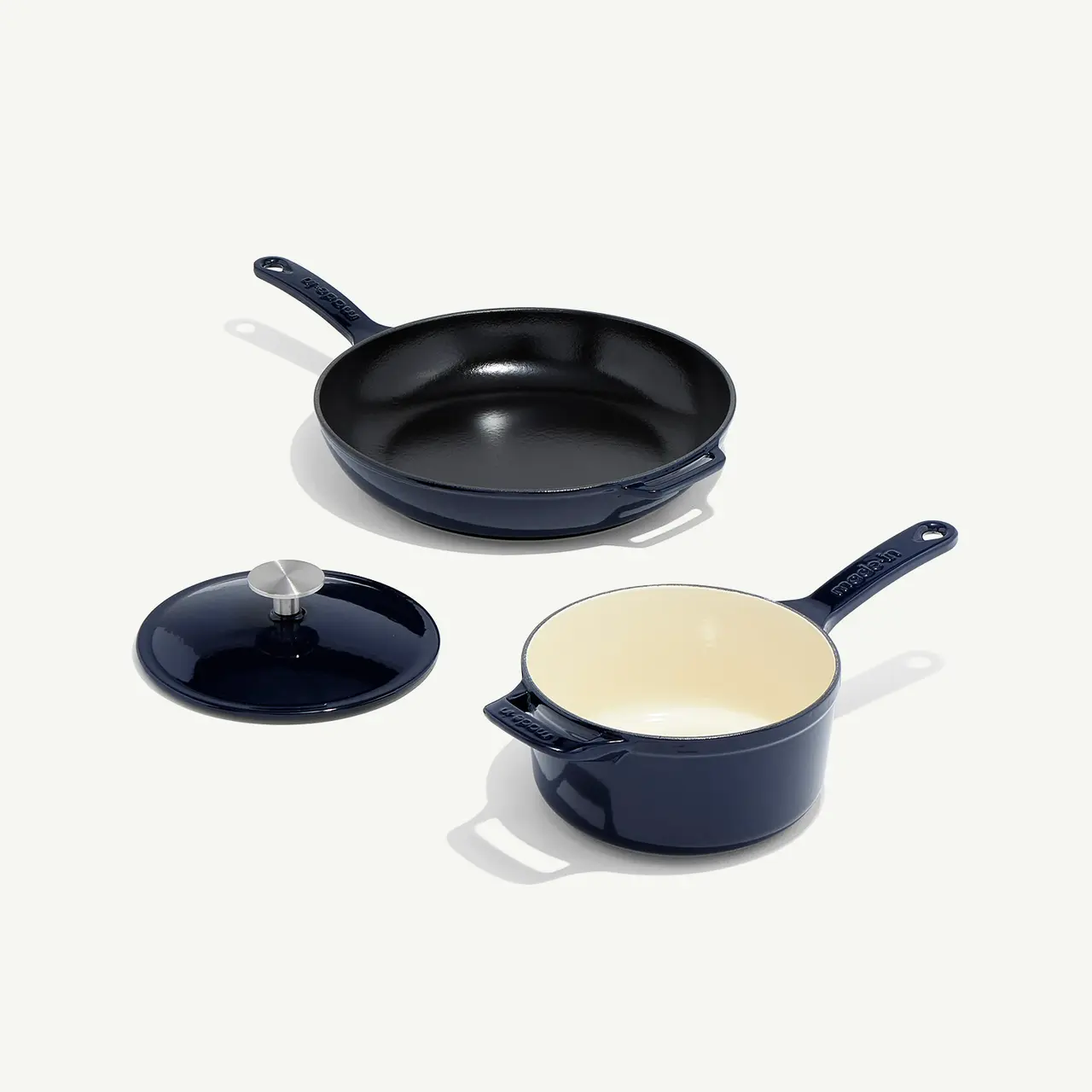 A set of dark blue cookware, including a skillet and a saucepan with a lid, arranged neatly on a light background.