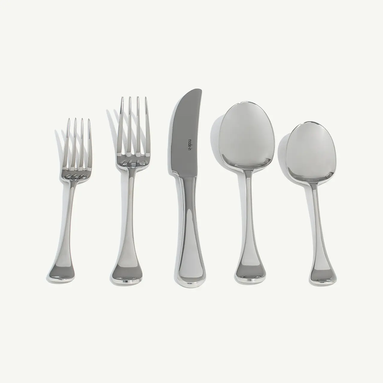 A set of silver flatware consisting of two forks, a knife, and two spoons arranged side by side against a light background.