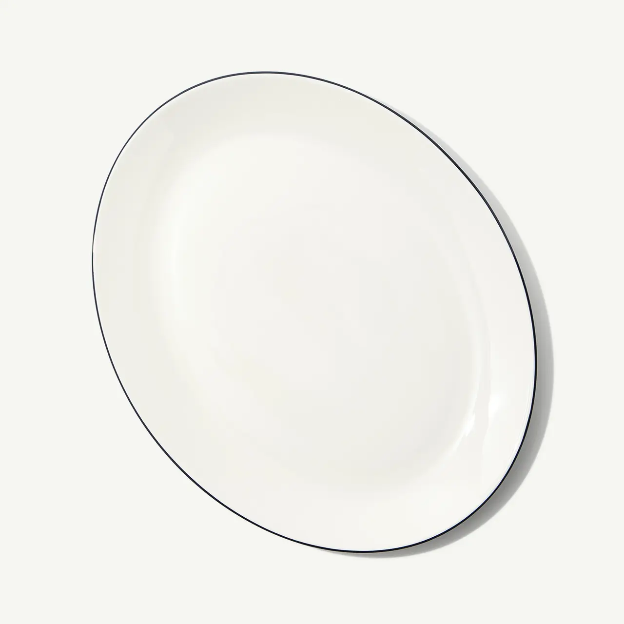 A plain white oval plate with a simple dark rim on a light background is displayed.