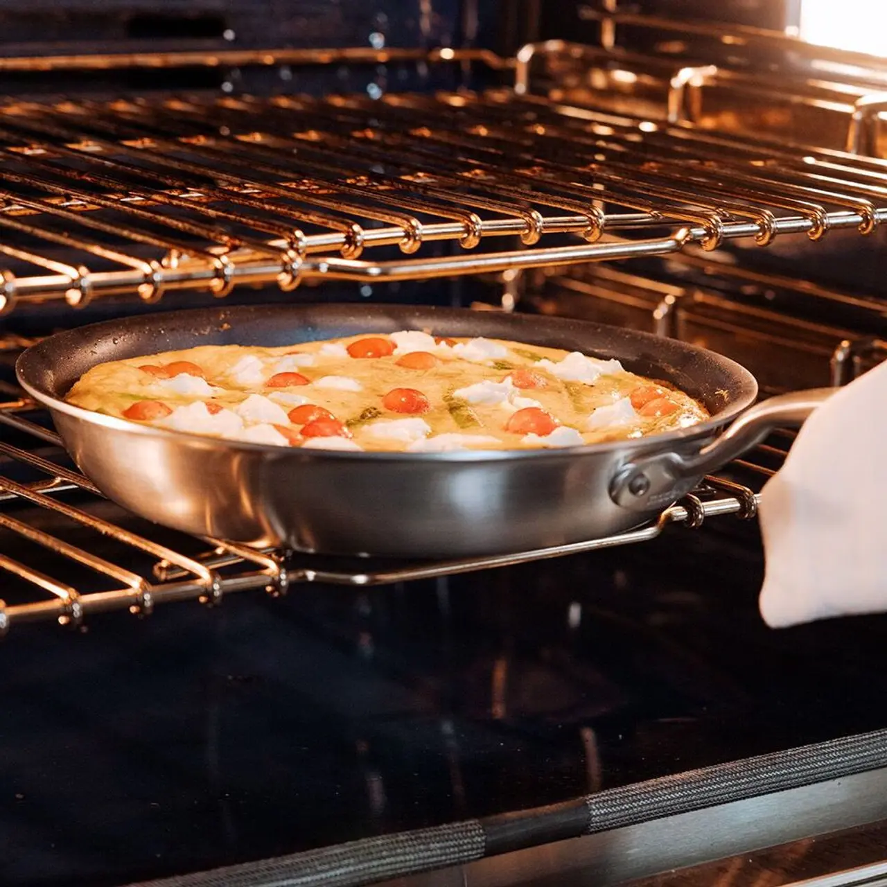 A large pan filled with a variety of vegetables is roasting in an oven.