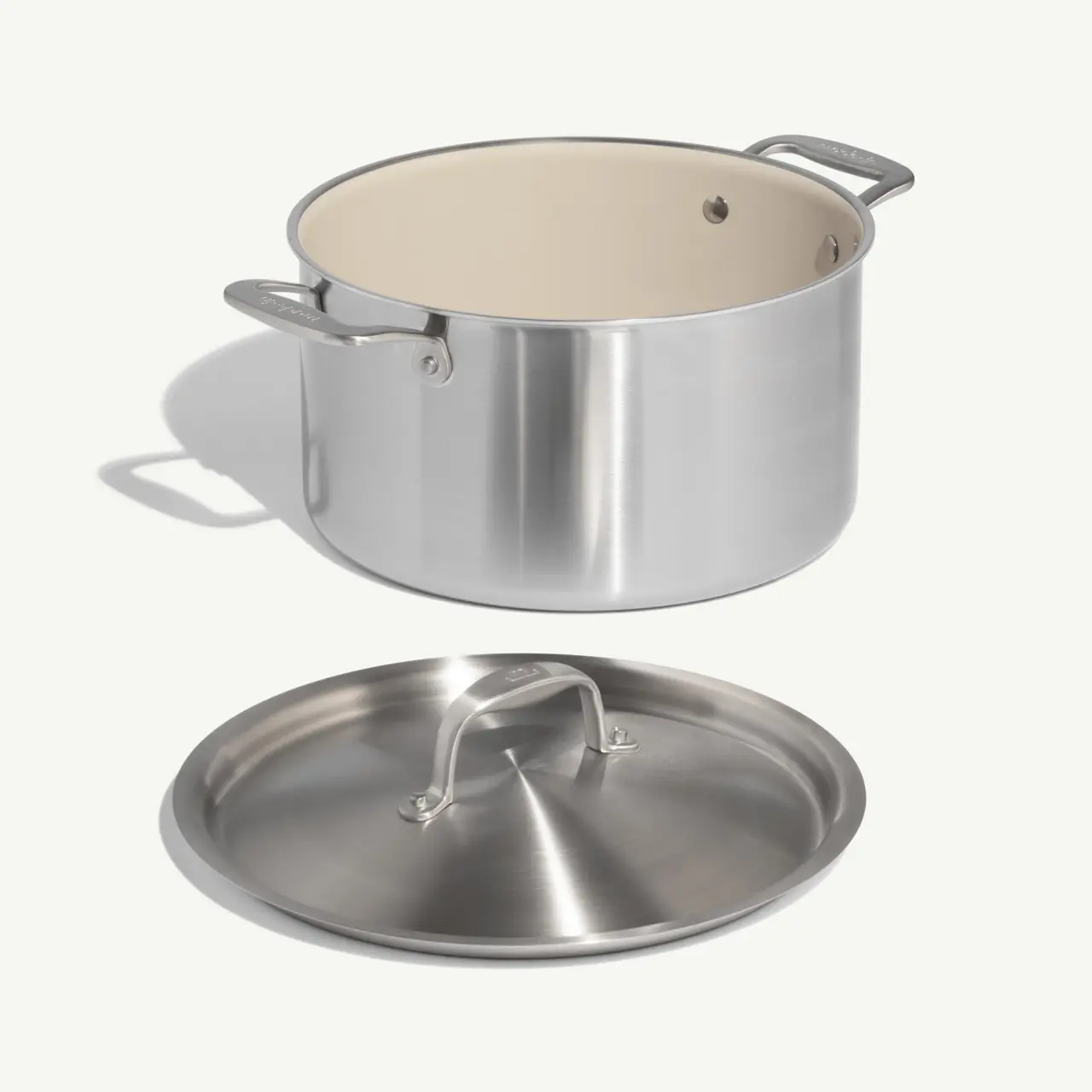 A stainless steel pot with a white interior and a matching lid is shown.