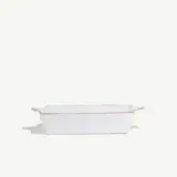 A white rectangular baking dish with red trim set against a plain background.