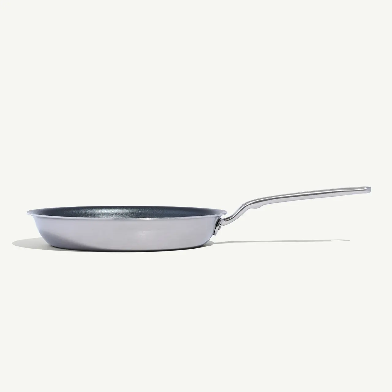 A side view of a frying pan with a long handle against a white background.
