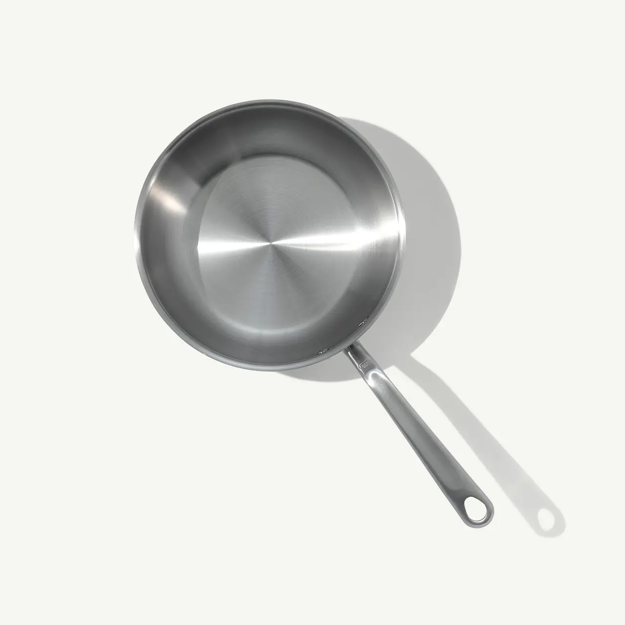 A stainless steel frying pan with a long handle is presented against a light gray background.