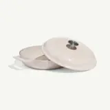 A round, cream-colored cooking pot with a matching lid, featuring a handle and a small vent on top.