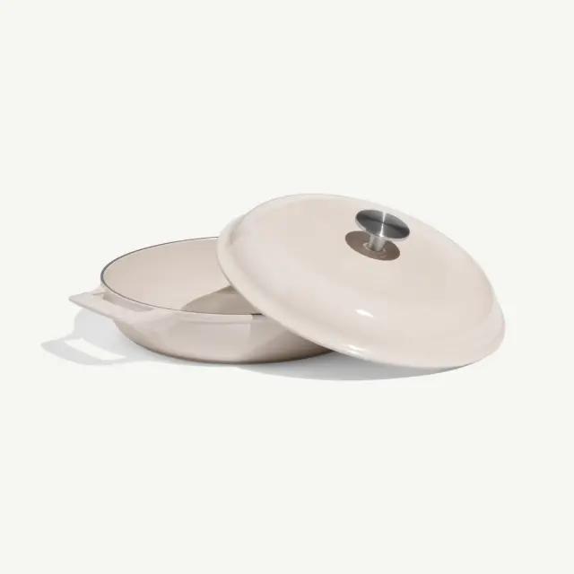 A round, cream-colored cooking pot with a matching lid, featuring a handle and a small vent on top.