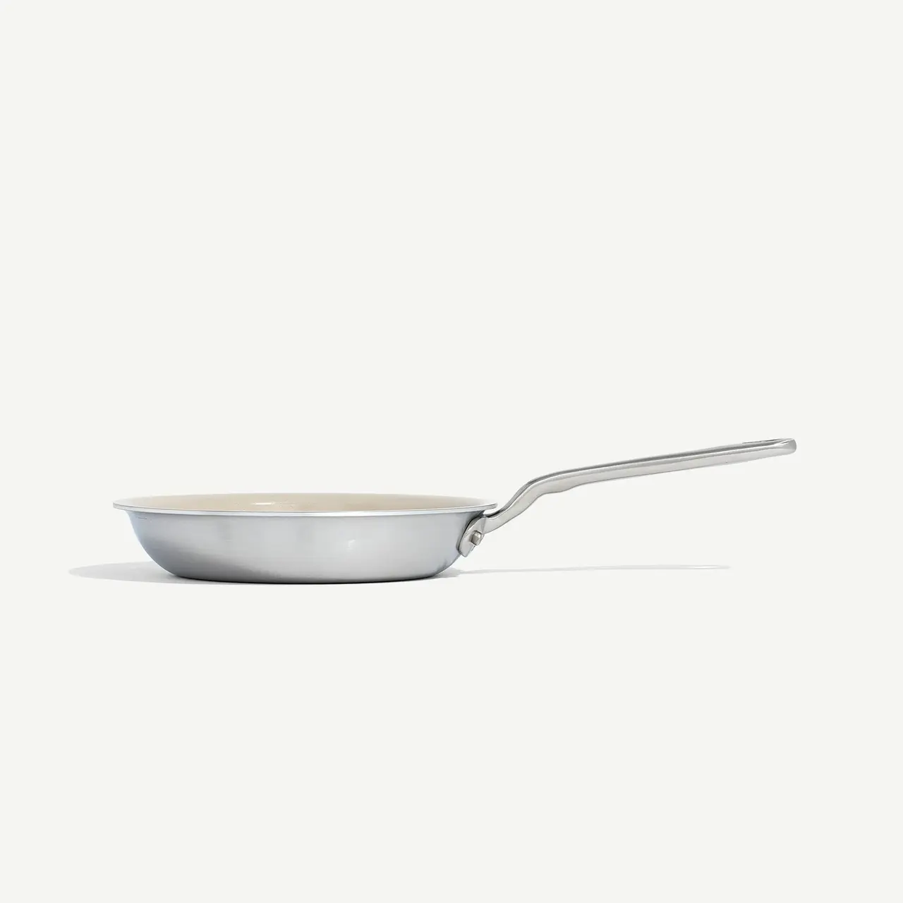 A stainless steel frying pan with a silver handle sits on a plain white background.