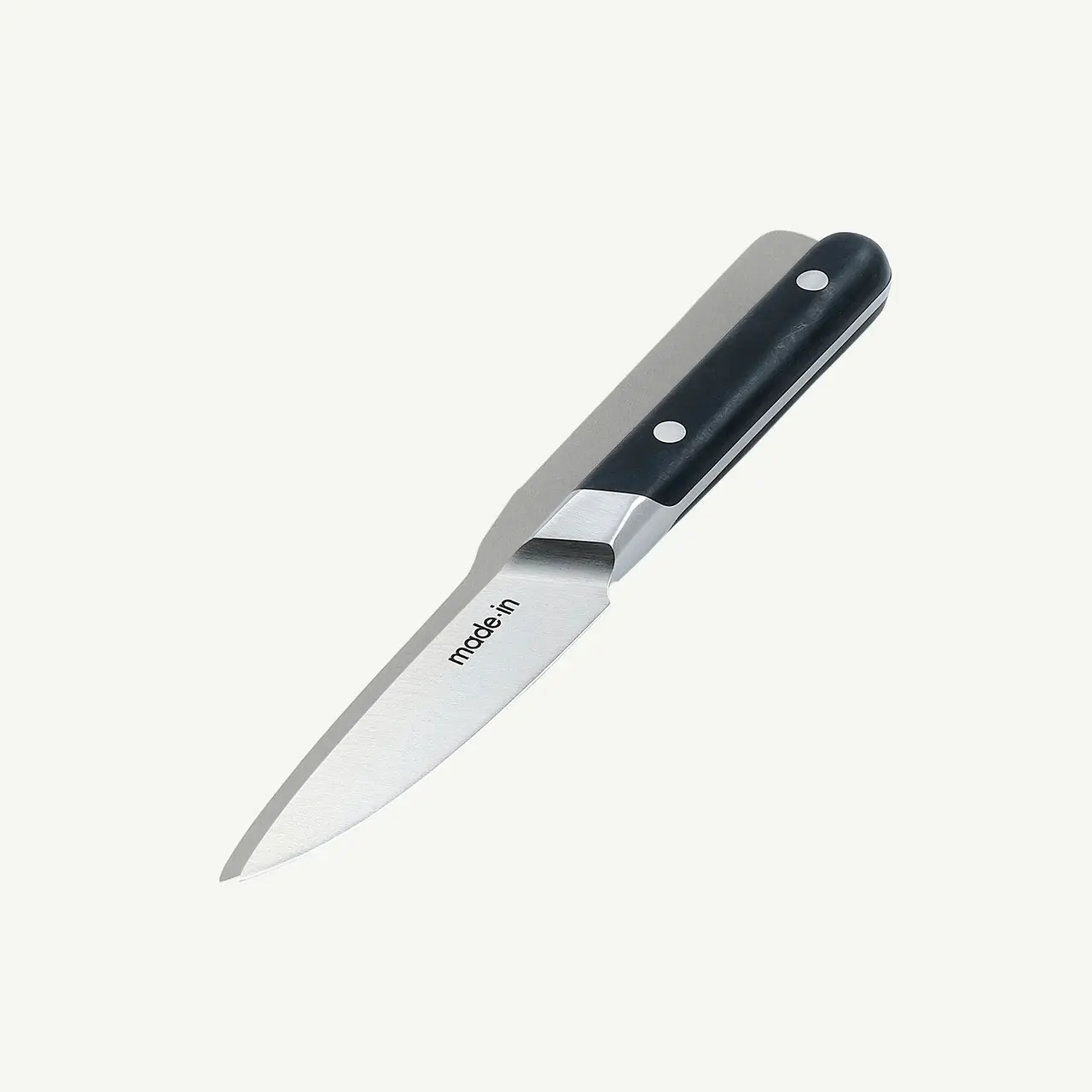 A stainless steel paring knife with a black handle is displayed against a white background.