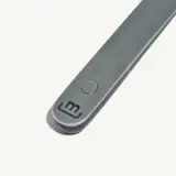 A close-up of a silver electronic device with a circular button and a logo with the letter 'm'.