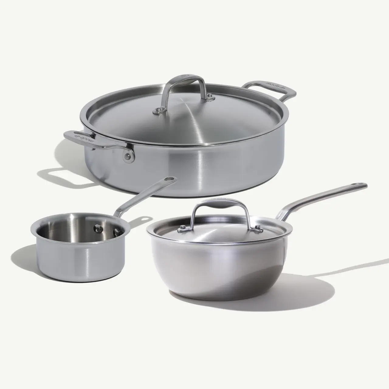 A set of three stainless steel cooking pots of different sizes with lids.