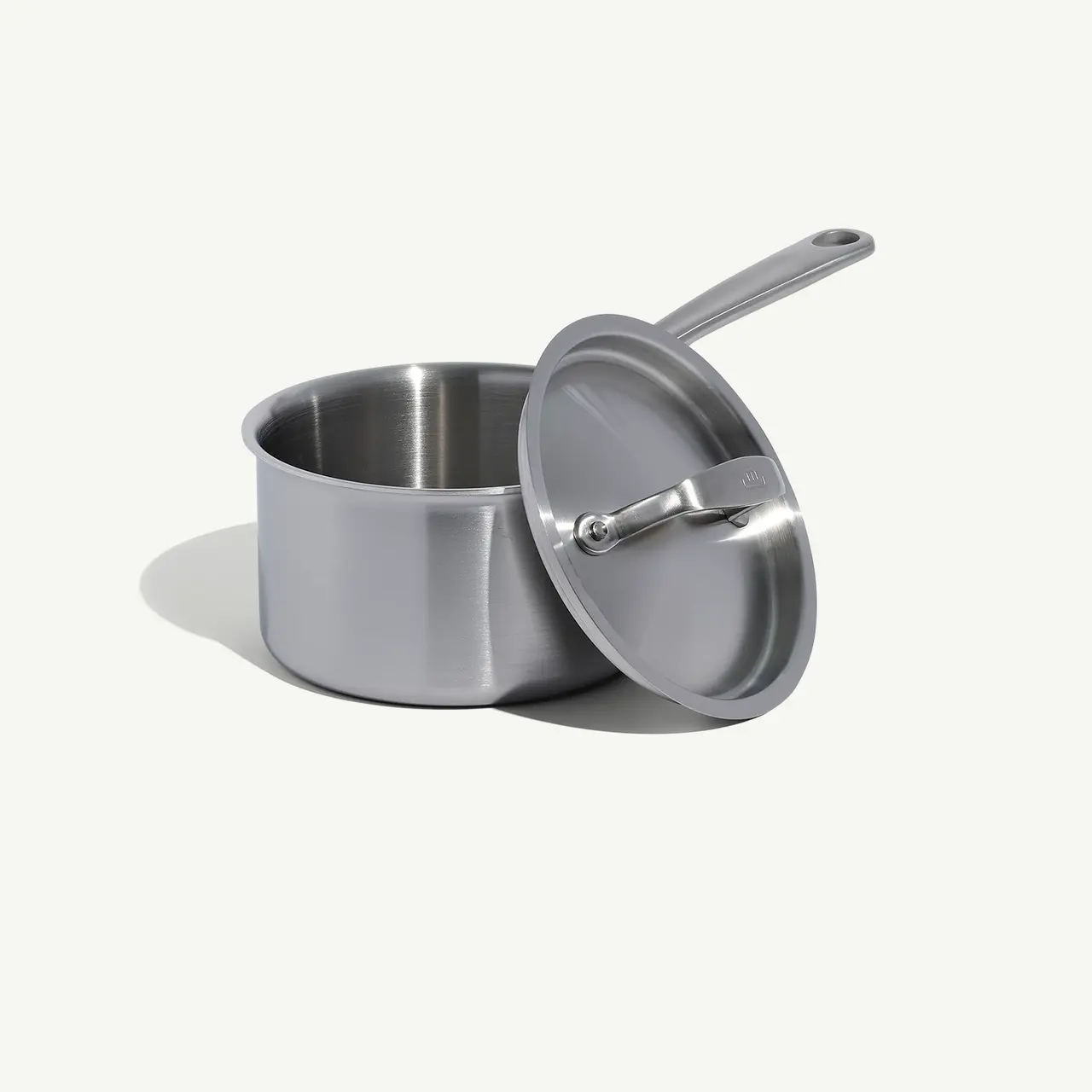 A stainless steel saucepan with a lid on a light background.