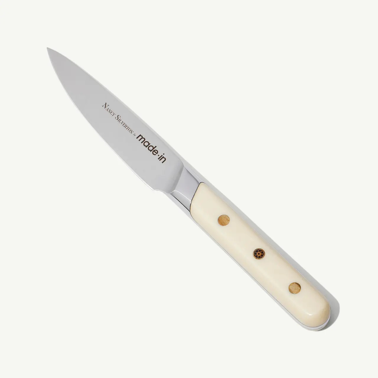 A sleek kitchen knife with a white handle and "Made In" text on its blade, isolated on a white background.