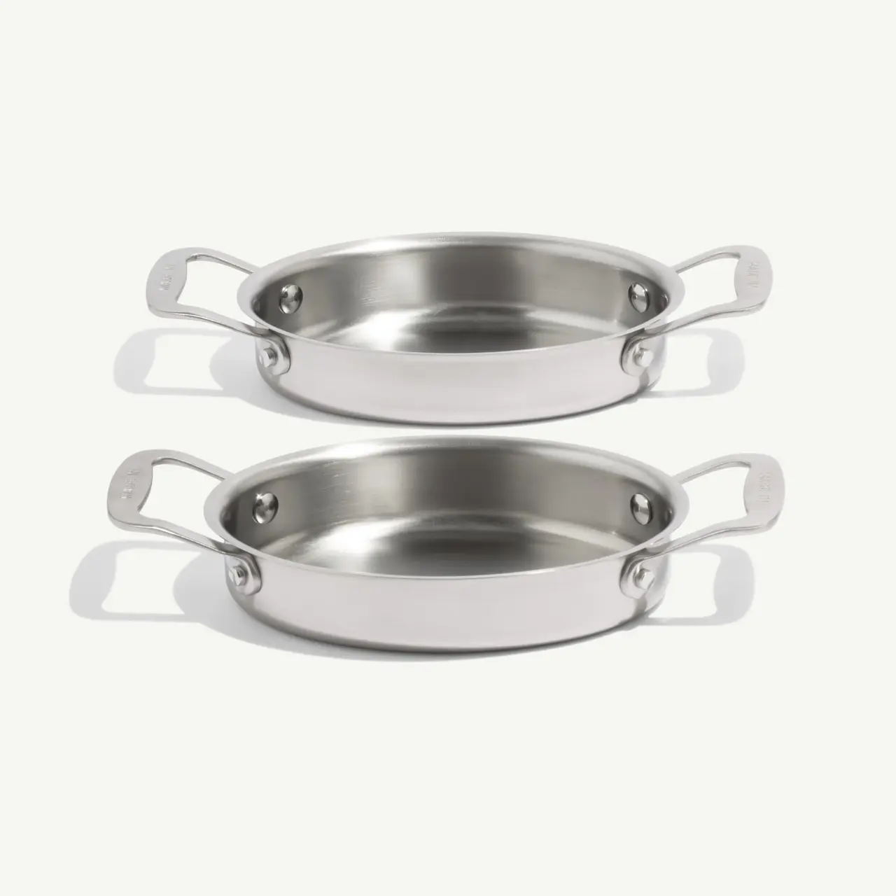 Two stainless steel oval baking dishes are stacked on top of each other.