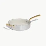 A stainless steel frying pan with a white interior and a gold-colored handle.
