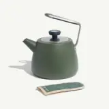 A green stovetop kettle with a stainless steel handle and a matching pot holder on a light background.