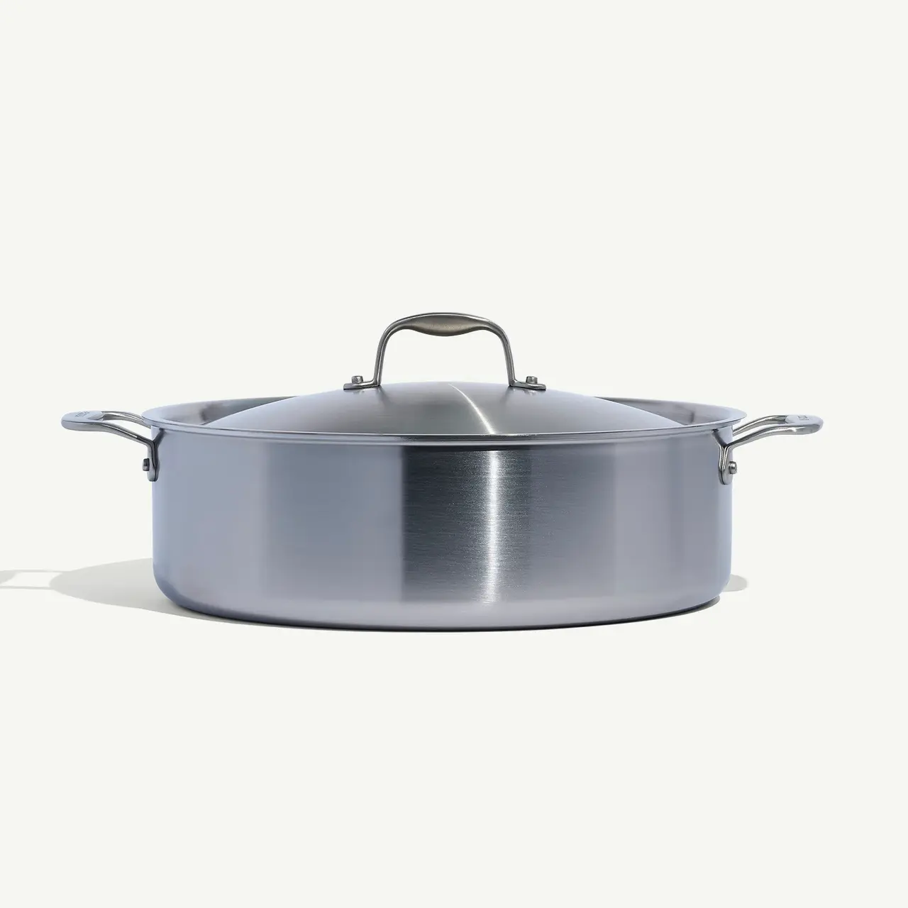 A stainless steel pot with a lid and two handles against a white background.