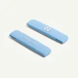 Two light blue hair clips featuring the text "CAROLINA" and the logo of the University of North Carolina.