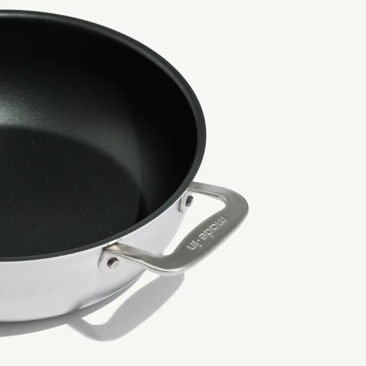 A silver and black frying pan is shown against a white background, highlighting its sleek design and handle.