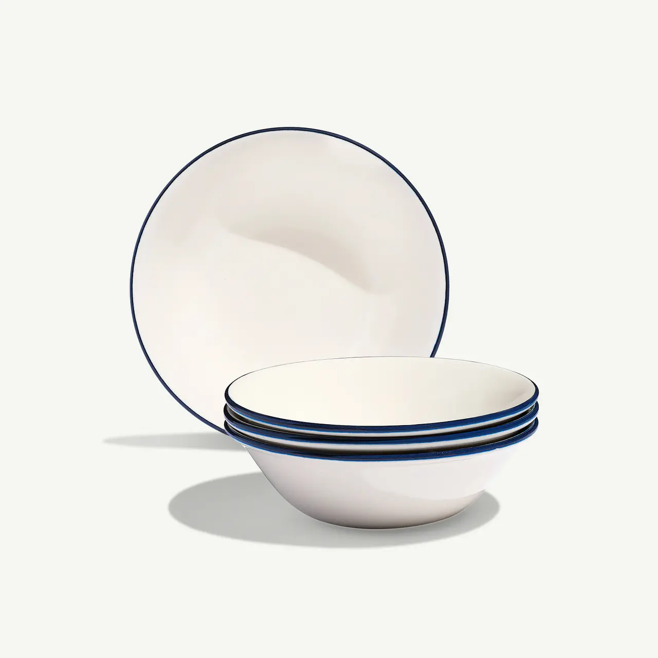 A stack of white bowls with blue trim lines near the edges sits in front of a standing matching plate with a plain backdrop.
