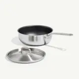 A stainless steel saucepan with a non-stick coating and a lid placed beside it on a light background.