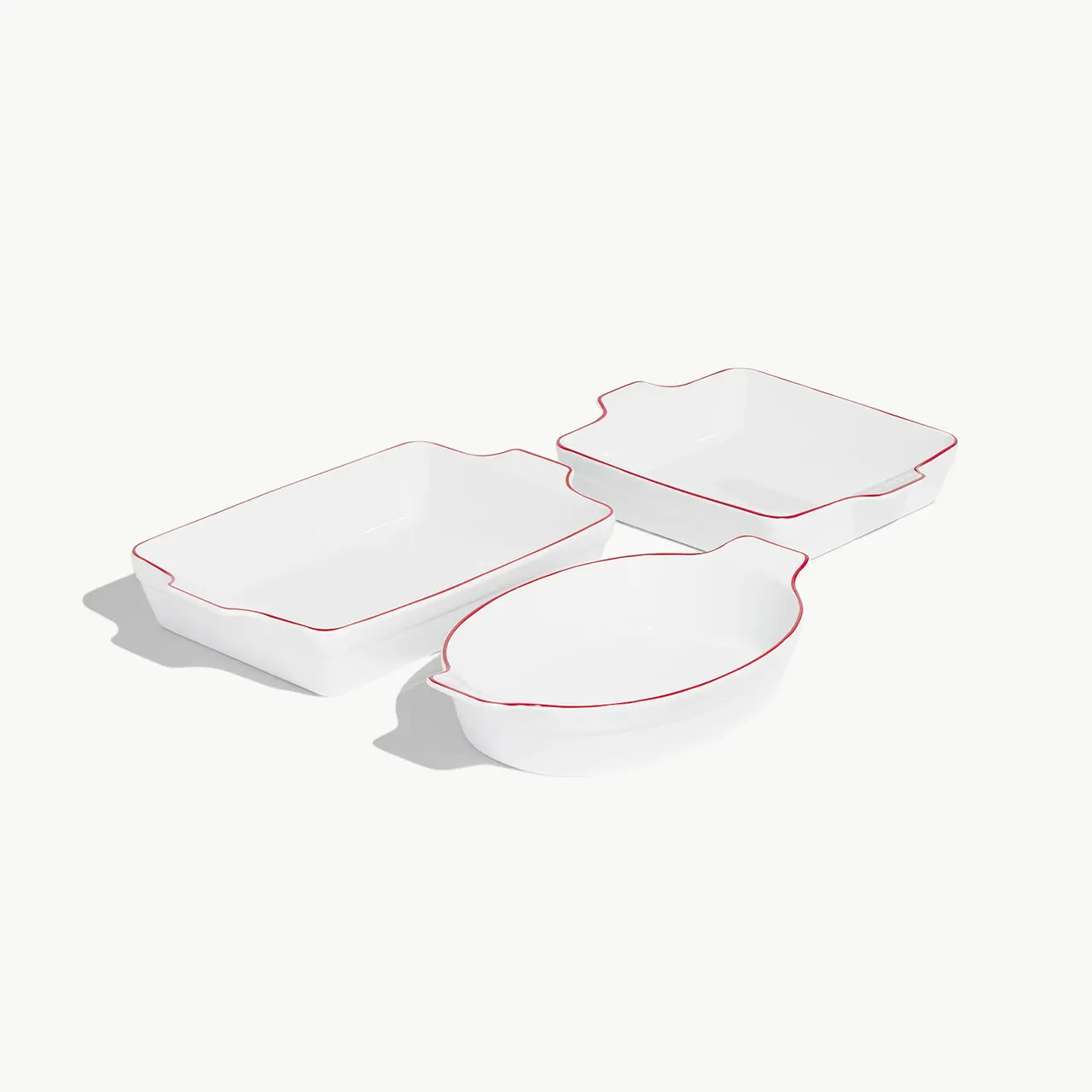 Three white serving dishes with red trim are presented on a light background.