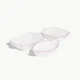 Three white serving dishes with red trim are presented on a light background.