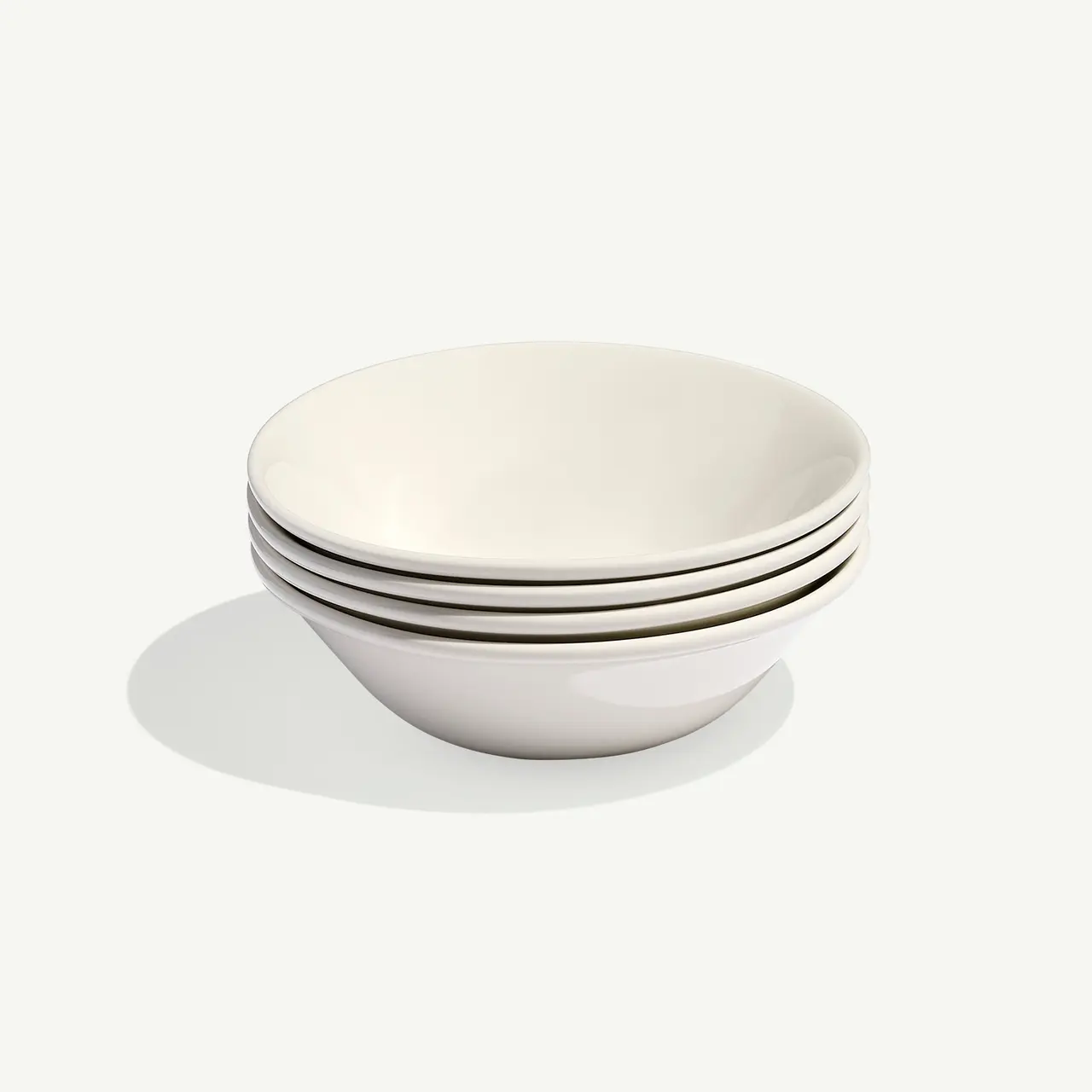 A stack of four white ceramic bowls on a light background.